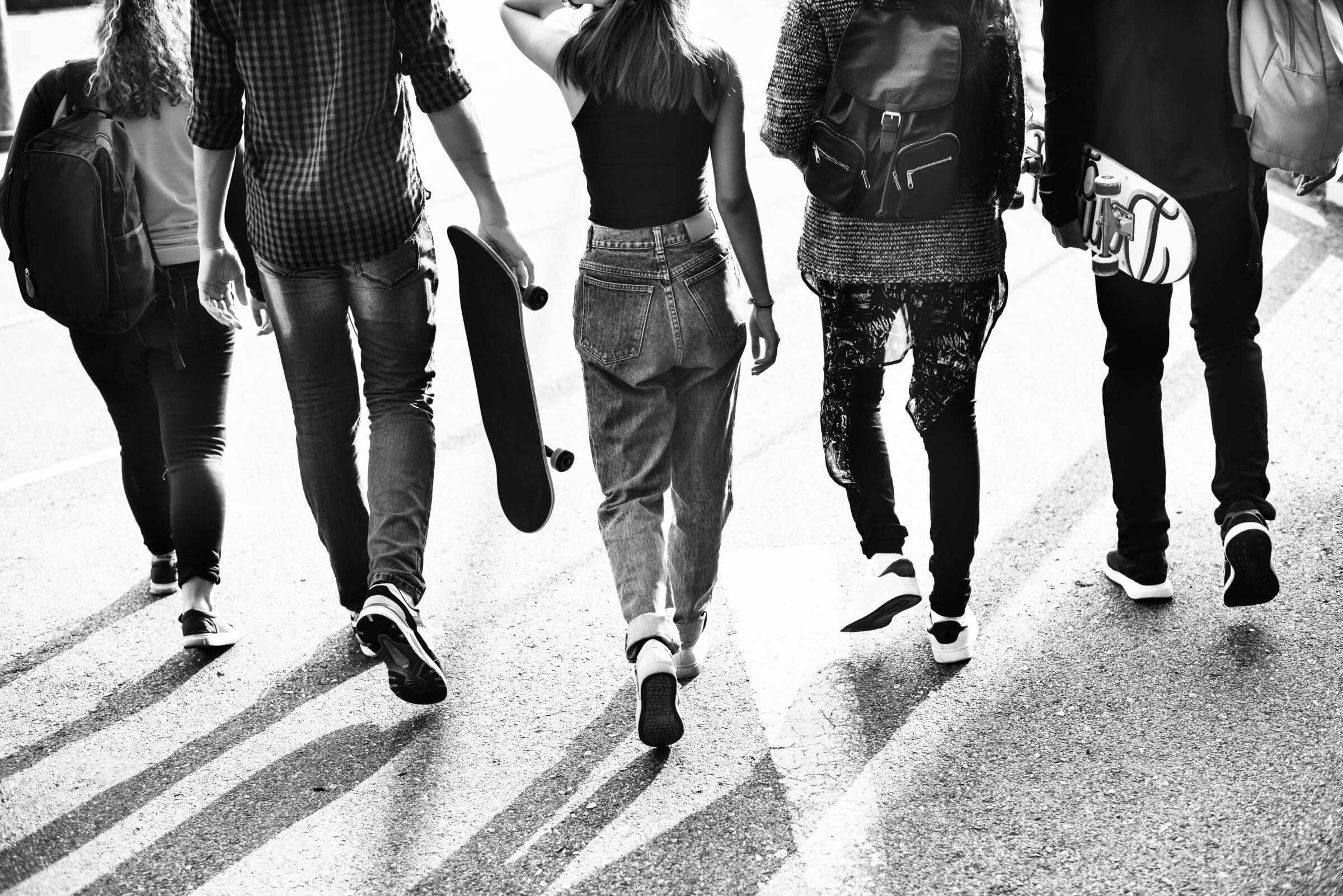 Un grupo de jóvenes camina por la calle; dos llevan skate